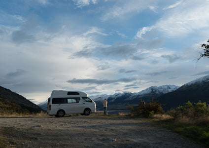The ultimate freedom of the open road in New Zealand. This photo captures a man taking in a breathtaking mountain view from the side of his campervan. This life of adventure is possible when you're not worried about your vehicle's safety. Between epic road trips, a secure vehicle storage space from Storage King acts as the perfect home base.