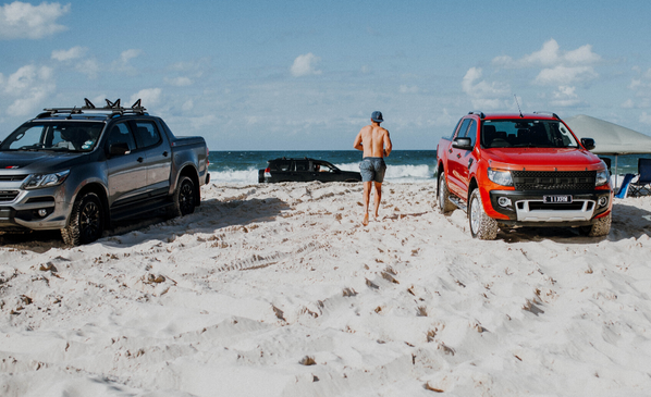This photo answers the question: "How can I manage owning multiple lifestyle vehicles?" It shows a person enjoying a beach day with their cars, representing a life full of passions. Our secure vehicle storage provides the perfect solution for the rest of your collection, whether it's a classic car, a 4x4, a boat, or a jet ski. We protect your assets, so you can enjoy the right one at the right moment.